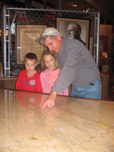 Museum Association Board Member Trey Bailey and his children look at a map of the 1920s Luling oilfield.