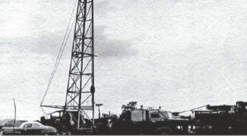Derrick and truck at first hydraulic fracture of oil well in 1949.