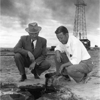 J.L. “Mike” Dougan, left, watches oil flow from his 1948 first Utah oil well