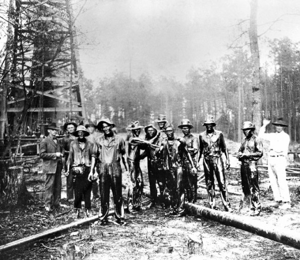 Oil drenched roughnecks photographed at 1922 Arkansas oil well.