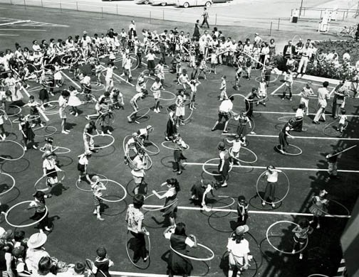 About 100 young people hula hooping together circa 1960.