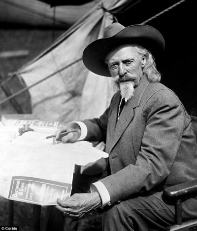 Exploring for Wyoming oilfields, William "Buffalo Bill" Cody studies maps at tent in field