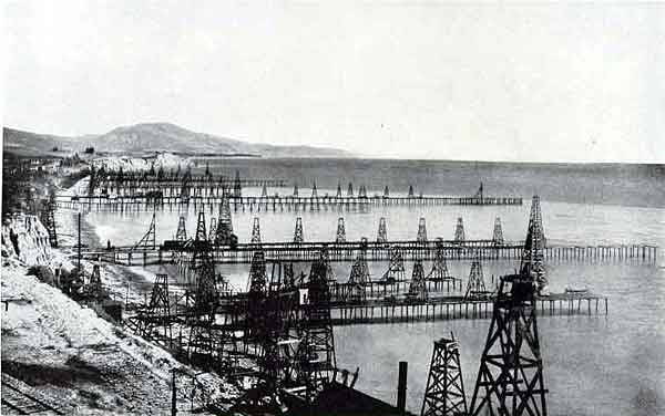 View of California oil piers with wooden derricks circa 1900.