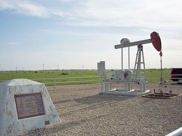 Pump jack at Kansas oil well with historic marker at the Stapleton No. 1 well commemorates the October 1915 discovery of the giant El Dorado oilfield.