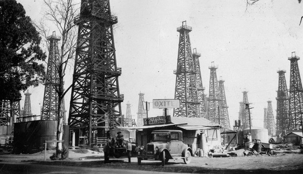 Derricks at Signal Hill, California with building in foreground, circa 1930.