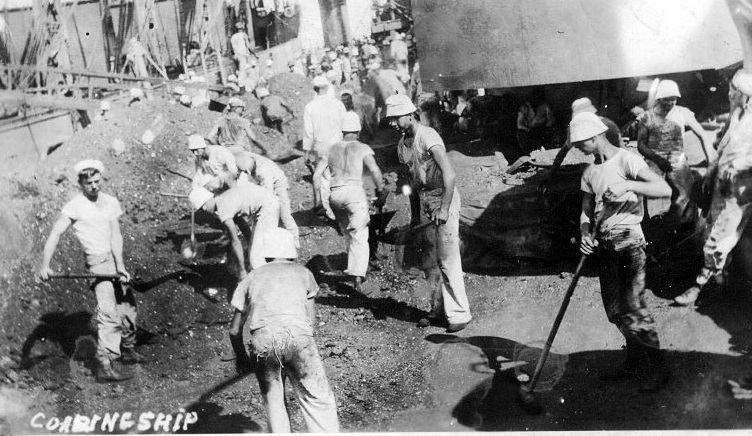 USS Texas at coaling barge as sailor shovel tons of coal