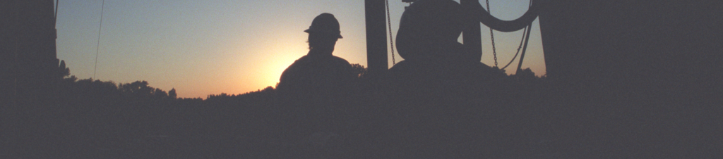 Artistic view of roughneck on an oil rig at sunset.