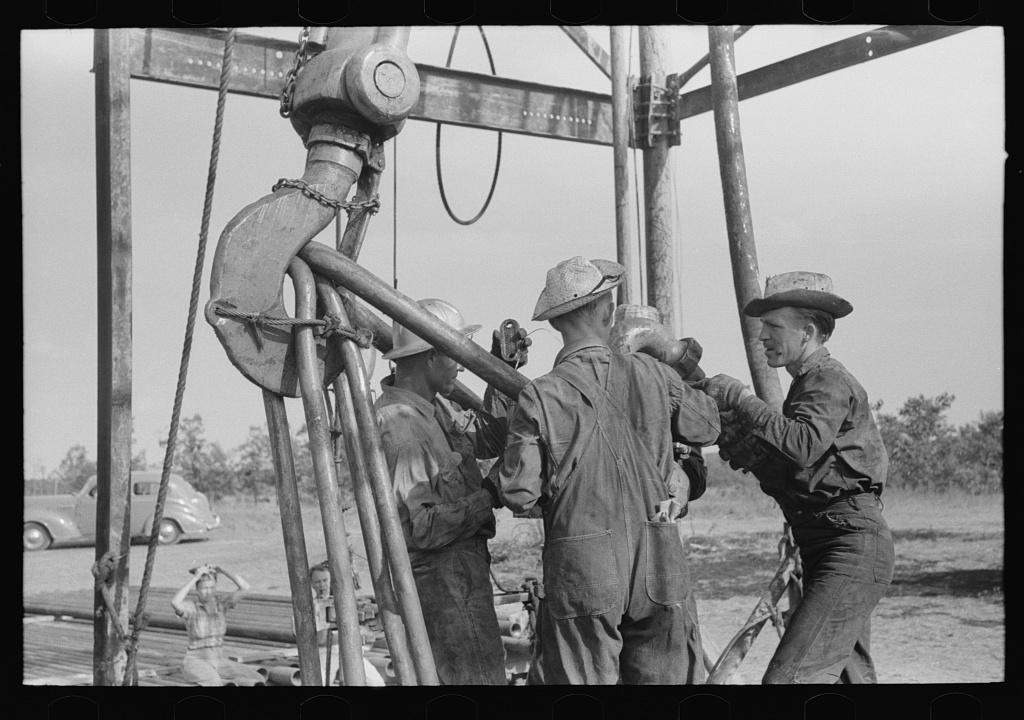 Oil workers working on lowered traveling block in August 1939 in Seminole, Oklahoma, oilfield.