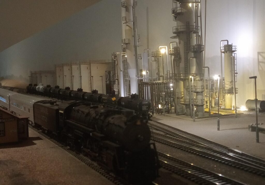 Night scene of train at refinery created by skilled a model railroader.
